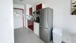 Una cocina compacta con refrigerador de acero inoxidable, microondas y lavavajillas.