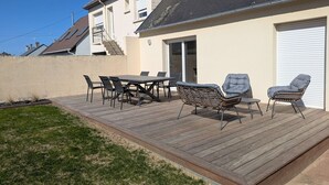Eine Terrasse mit Tisch und Stühlen, eine überdachte Veranda und eine Garagentür.