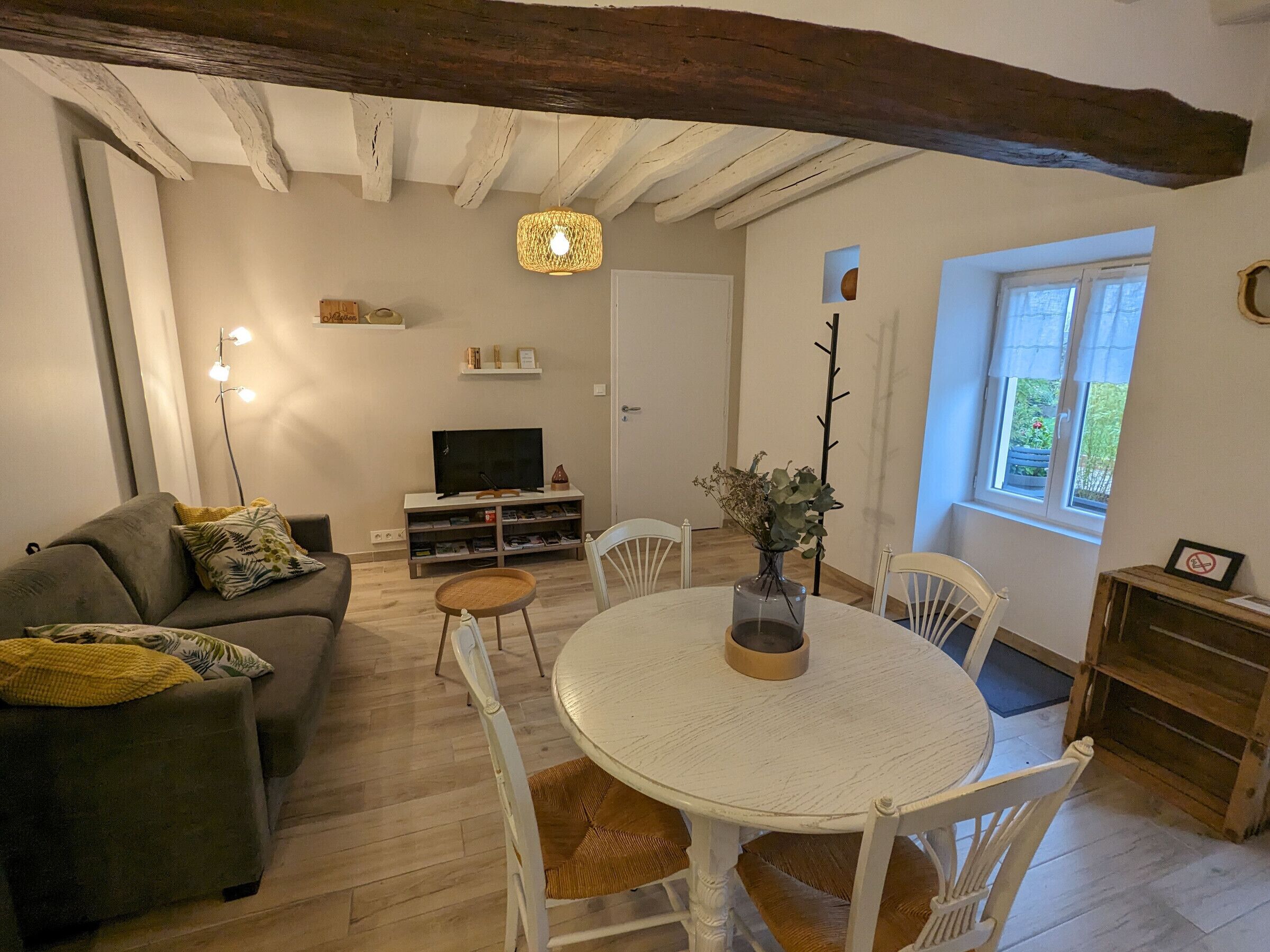 Een gezellige woonkamer met een bank, een ronde eettafel en een televisie.