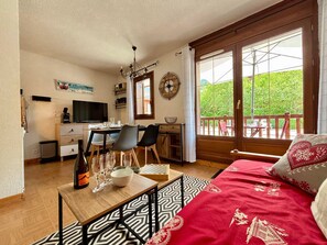 A room with a bed, a desk, a TV, and a dining table with chairs.