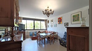 A spacious dining area with a large table and chairs, a chandelier, and artwork on the walls.
