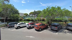 A parking lot with several cars, trees, and a building in the background.