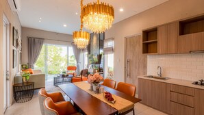 Una cocina moderna con armarios de madera, una isla grande y un comedor con sillas anaranjadas.