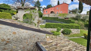 Una escalera de piedra que sube hacia un edificio rojo con un muro de piedra y un pequeño jardín.