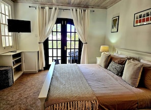 A bedroom with a bed, curtains, a TV, a lamp, and a framed picture on the wall.