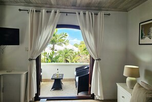 A room with a view of a balcony, a table with wine glasses, and a chair.