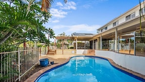 A swimming pool with a wooden deck, surrounded by a metal fence and palm trees. - Serene Lakefront Water side Villa with Private Pool  (Westlake)