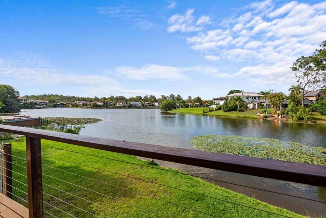 Vista de un lago con nenúfares, rodeado de casas y follaje verde.