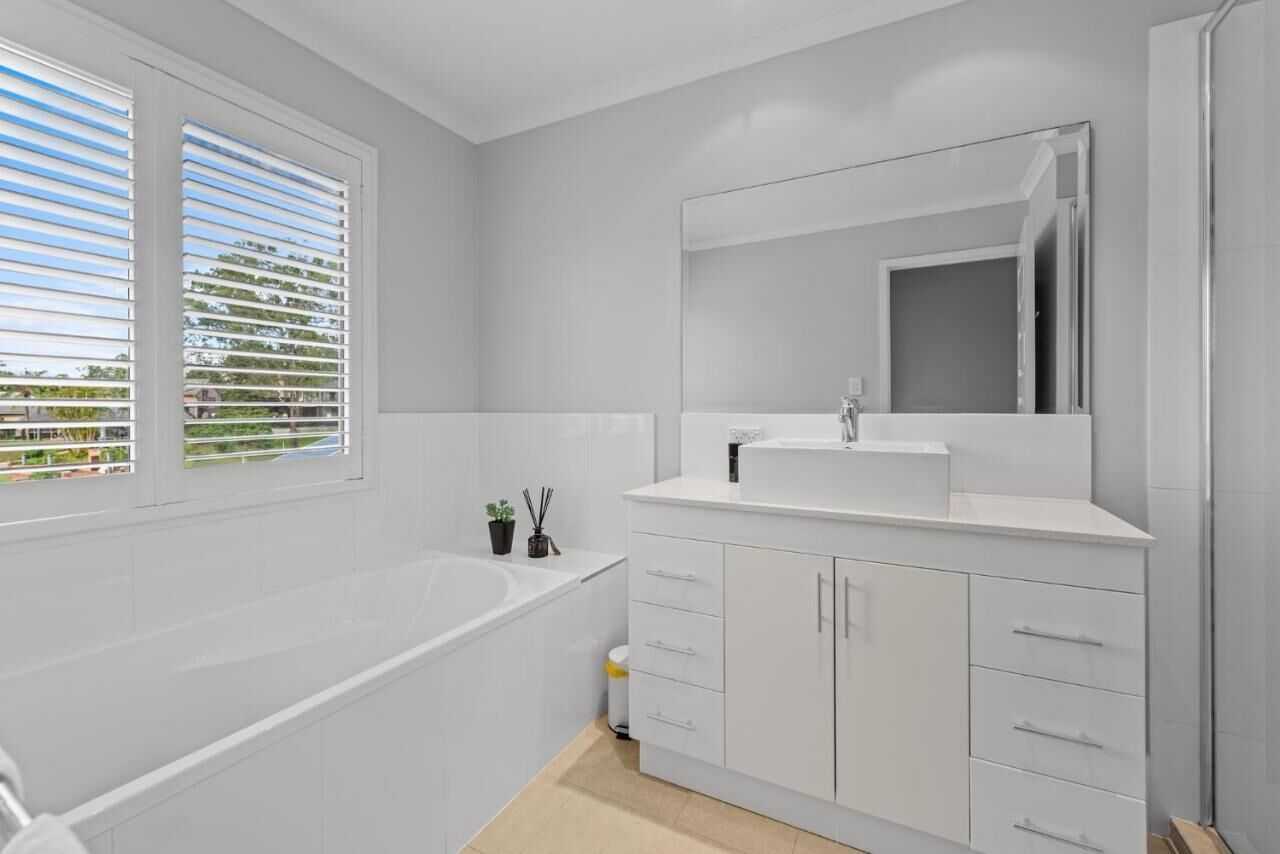 A modern bathroom with a bathtub, a sink, and a large mirror.