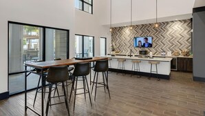 Une cuisine moderne dotée d’un grand îlot central, de tabourets de bar et d’un téléviseur fixé au mur.