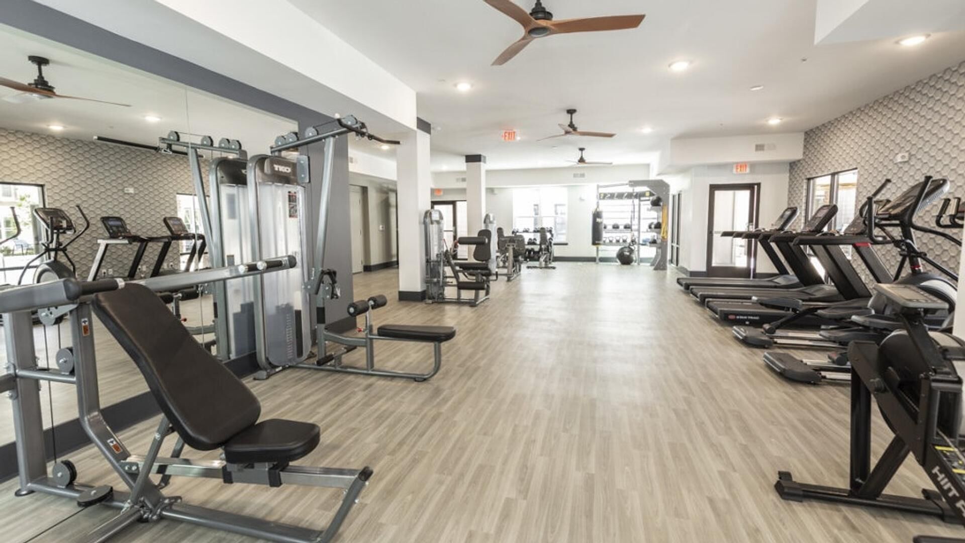 A gym with various exercise equipment, including treadmills, weight machines, and free weights.