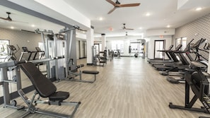 A gym with treadmills, weight machines, and a mirror wall.