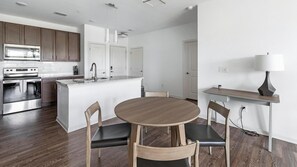 Une cuisine moderne dotée d’appareils électroménagers en acier inoxydable, d’un îlot central avec des sièges et d’un coin repas comprenant une table et des chaises.