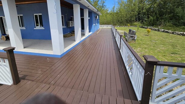 Een blauw gebouw met een overdekte veranda en een houten terras.