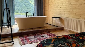 A room with a large bathtub, a view of a mountain, and a wooden ceiling. - Kazbegi Inn Cottages  (Kazbegi)