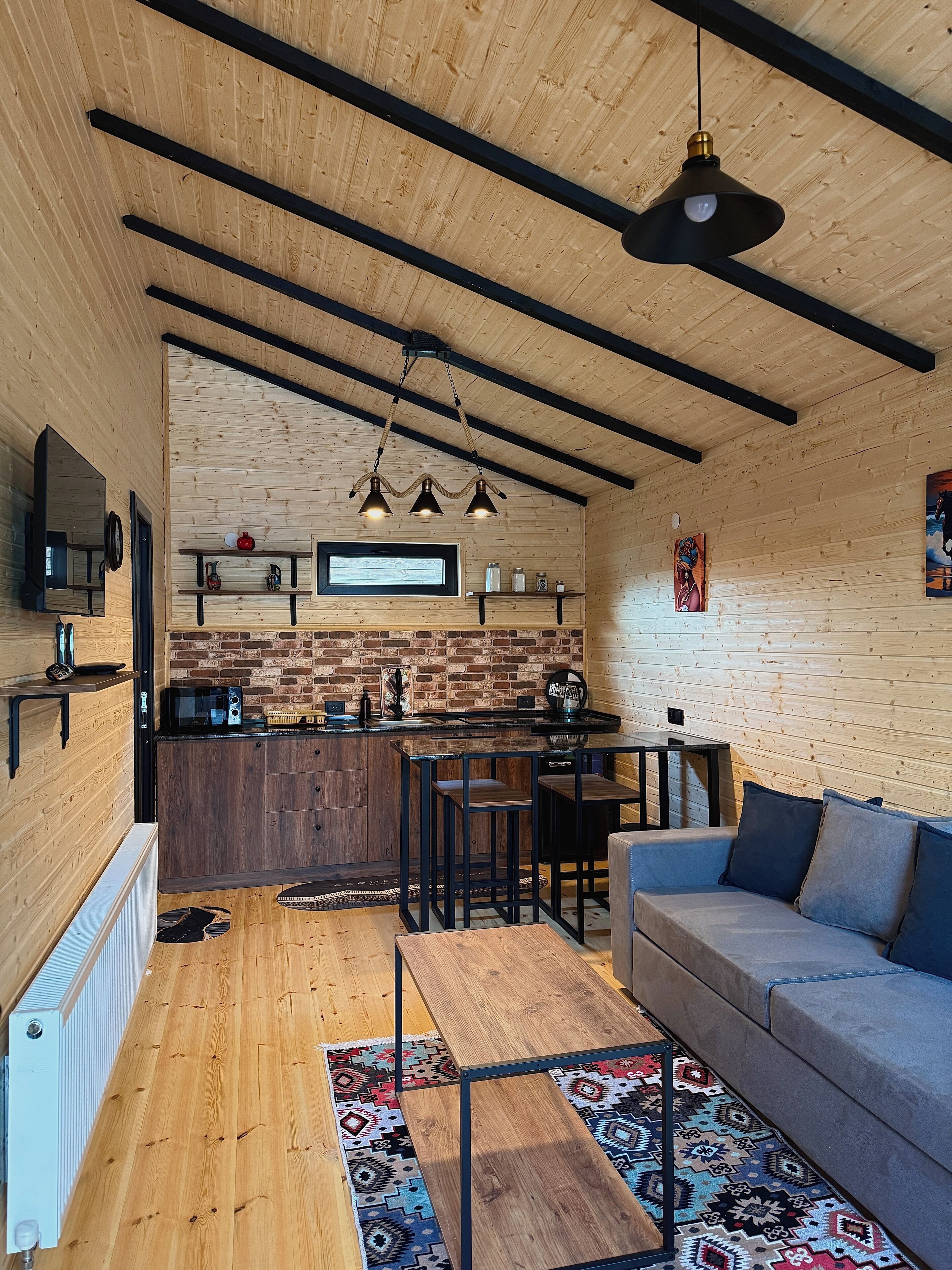 A modern kitchen with a brick backsplash, wooden beams, and a bar area.