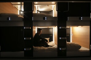 A bunk bed room with a person sitting on the lower bunk. - PLAZA EAST CABIN - Caters to men (Yokote)