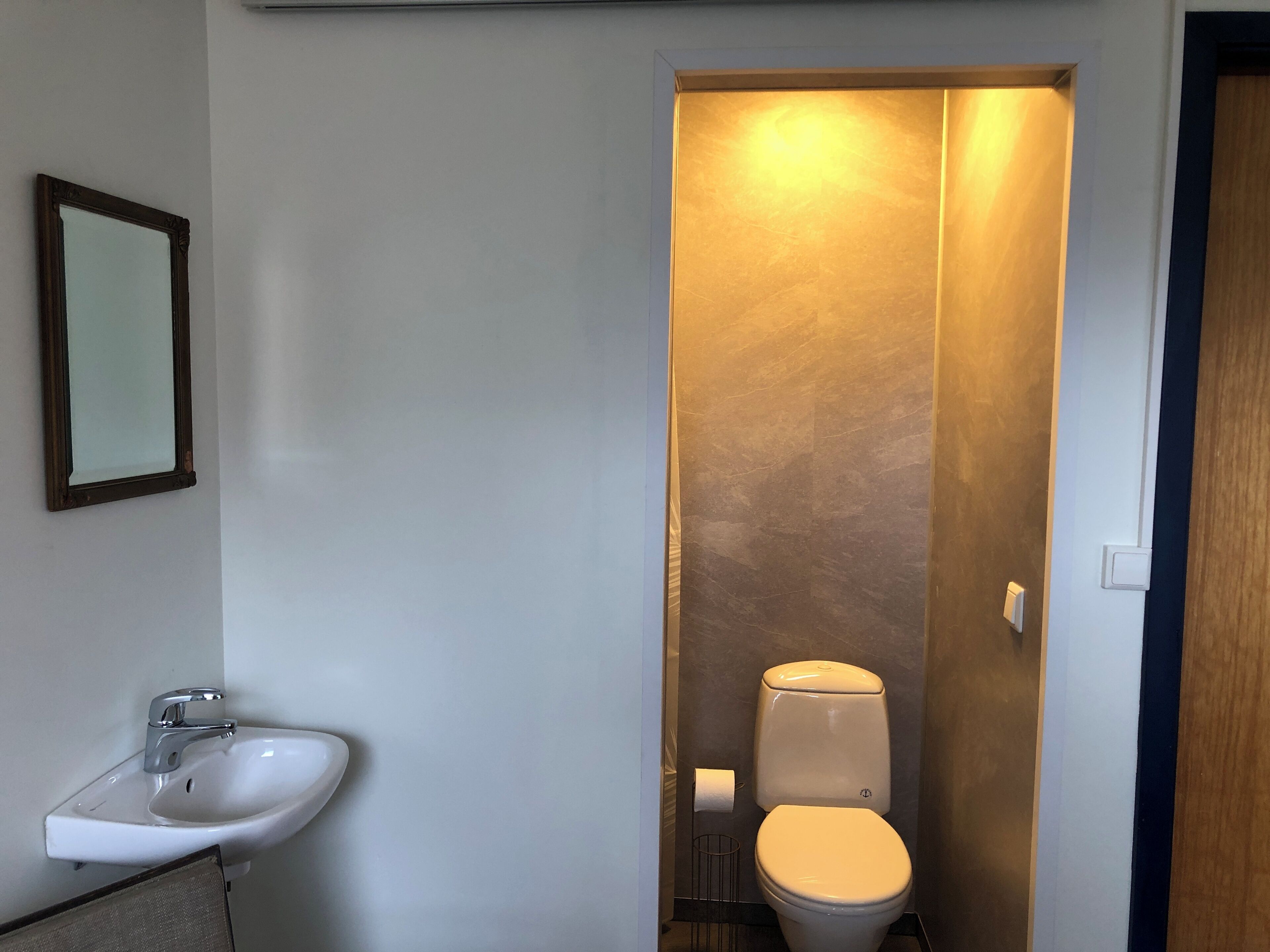A bathroom with a white sink, a toilet, and a mirror on the wall.