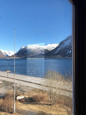 A view of a lake with mountains in the background, a road in the foreground, and a clear sky. - Jølster Lake View (Sunnfjord)