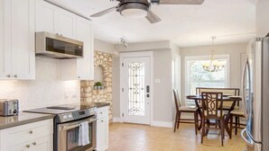 A kitchen with white cabinets, a built-in oven, a microwave, and a ceiling fan. - The Family Retreat in Dripping Springs (Dripping Springs)