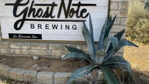 A sign for Ghost Note Brewing with a rustic wooden background and a stone wall. - The Family Retreat in Dripping Springs (Dripping Springs)