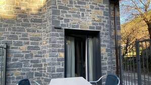 A stone building with a patio, a table, and two chairs.
