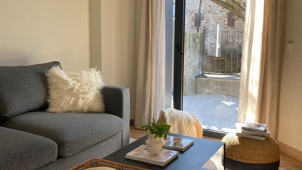 A modern living room with a grey sofa, a black coffee table, and a wicker basket.