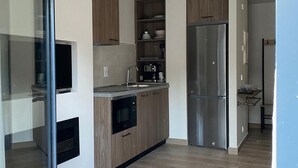 A modern kitchen with wooden cabinets, a stainless steel refrigerator, and a built-in oven.