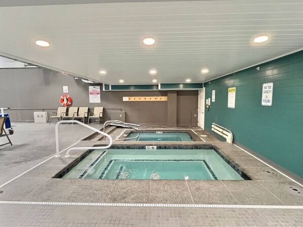 Piscina coperta con due corsie, segnaletica di sicurezza e posto di salvataggio.
