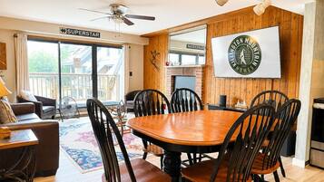 A dining area with a wooden table and chairs, a ceiling fan, and a large mirror on the wall.