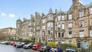 A row of terraced houses with a parking lot in front.