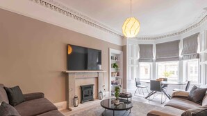 A modern living room with a fireplace, sofa, coffee table, and a TV mounted on the wall.