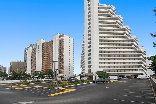 A parking lot with multiple cars and a large building with a unique zigzag design.