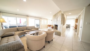 Un salon spacieux avec un grand canapé, deux fauteuils, une table basse et une cheminée.