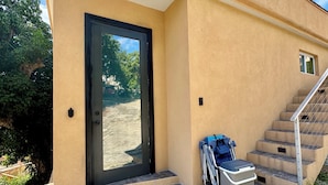A building entrance with a black door, a set of stone steps, and a blue wheelchair. - Sunset Hideaway Suite - Oceanview/central to Cruz Bay  (St John)