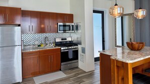 A modern kitchen with wooden cabinets, stainless steel appliances, a herringbone tile backsplash, and pendant lighting. - Sunset Hideaway Suite - Oceanview/central to Cruz Bay  (St John)