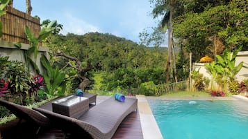 Relax by the serene pool surrounded by lush greenery and tropical plants.