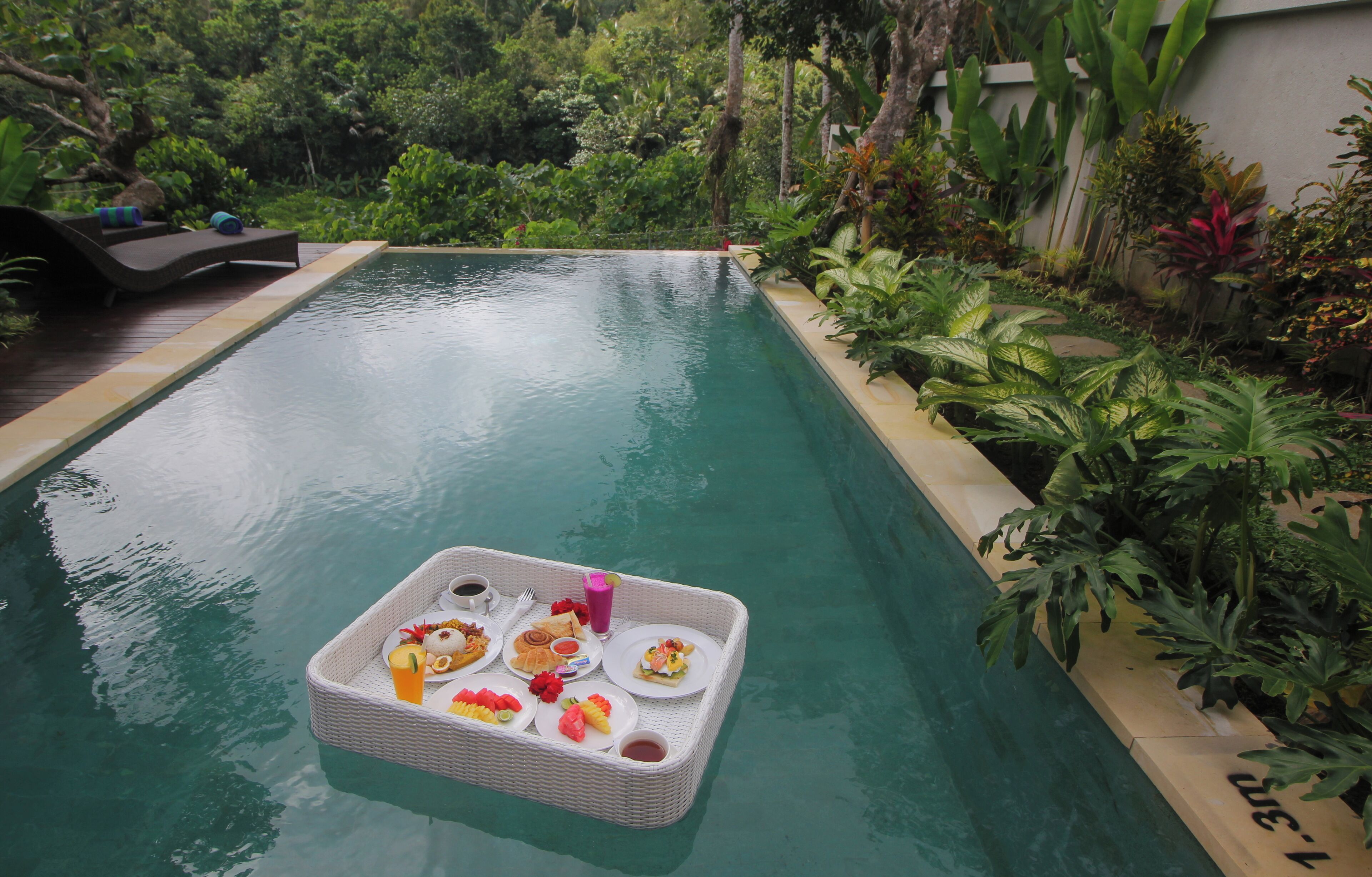 A poolside dining setup with a tray of food and drinks.