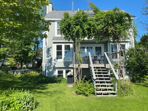 Une maison à deux étages avec un porche à l’avant, un escalier menant au deuxième étage et un petit jardin.