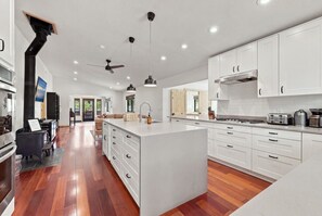 A modern kitchen with white cabinetry, a central island, and a wooden floor.