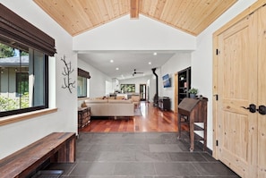 A spacious living area with a wooden bench, a sofa, and a dining table. - Mountain Pine Memories - Pets + Hot tub + Fire pit (South Lake Tahoe)