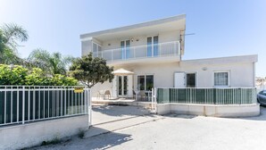 A two-story building with a balcony, a covered outdoor seating area, and a gated entrance.
