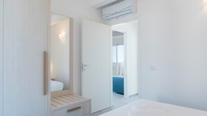 A modern bedroom with a large mirror, a wardrobe, a bed, and a view of a balcony.