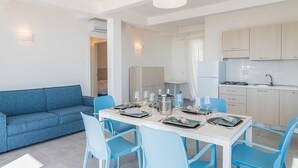 A modern kitchen with a gas stove, a refrigerator, and a dining area with a table set for four.