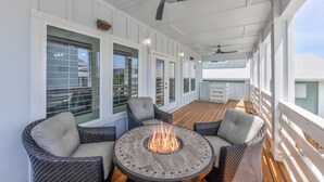 A covered outdoor deck with a fire pit, wicker furniture, and a ceiling fan. - Over the top construction, beautifully decorated, close to everything Port A has (Port Aransas)