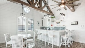 A modern kitchen with white cabinetry, a granite countertop, and a bar area with white stools. - Over the top construction, beautifully decorated, close to everything Port A has (Port Aransas)
