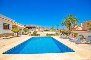 A swimming pool with lounge chairs and palm trees in a sunny outdoor setting. - Mediterranean Style Villa in Quesada Centre private pool walking distance to all (Ciudad Quesada)