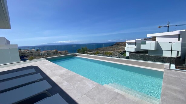 Ein Pool auf dem Dach mit freiem Blick auf den Ozean und entfernte Gebäude.