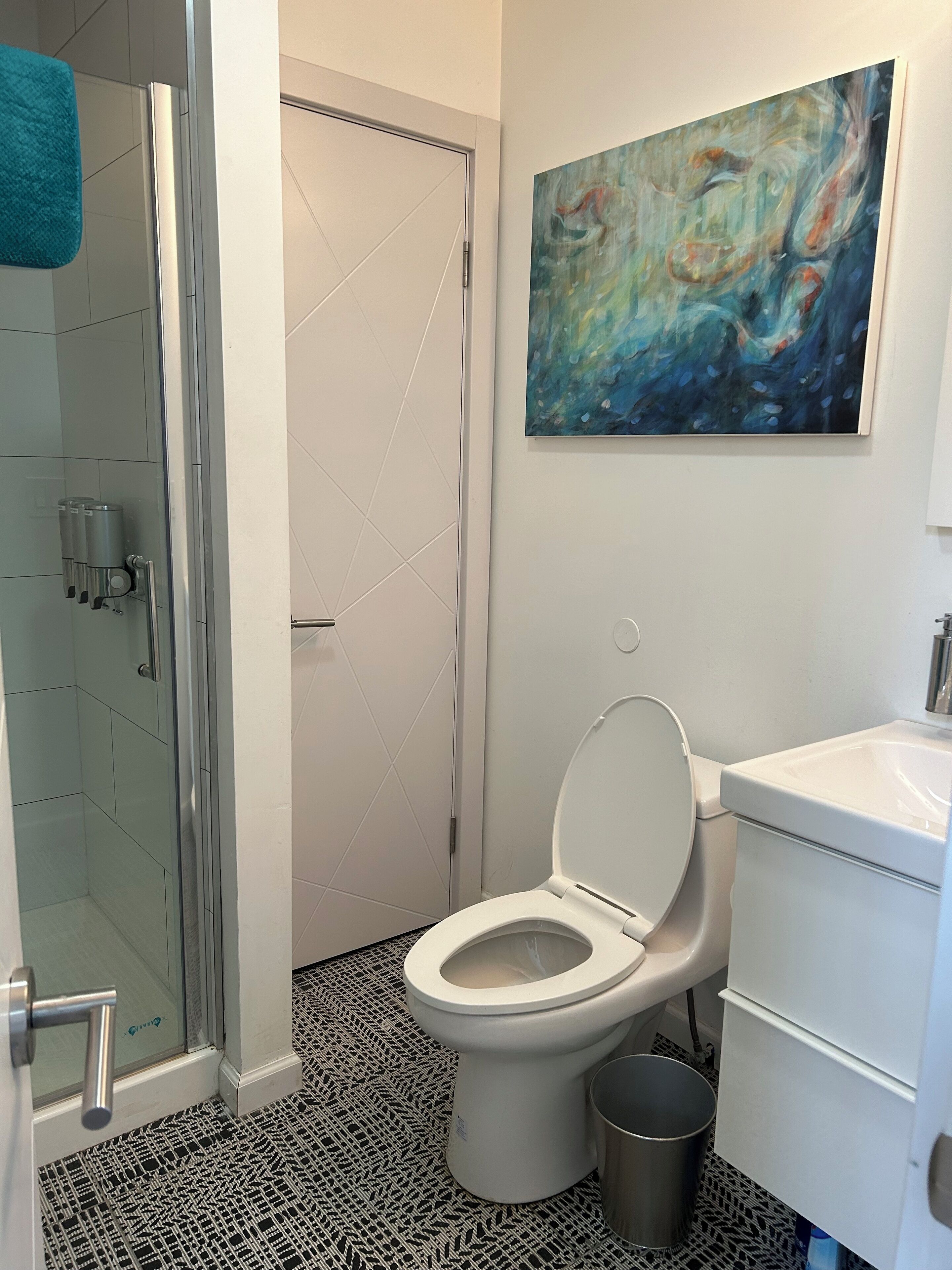 A bathroom with a toilet, a sink, a shower, and a glass door.