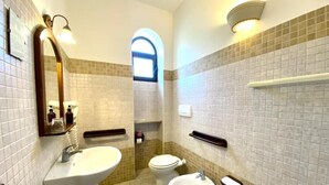 A bathroom with a sink, toilet, bidet, and a mirror.